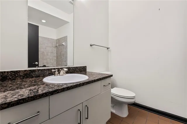 a bathroom with a granite countertop sink a toilet and a mirror