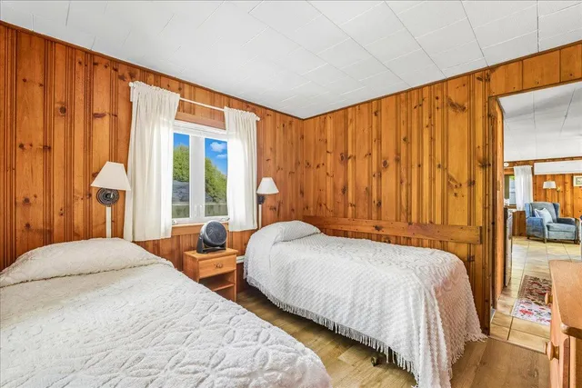 a bedroom with two beds and next to a window