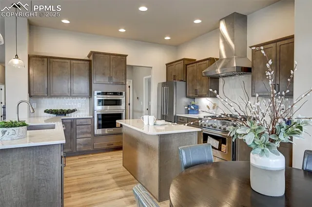 a kitchen with stainless steel appliances kitchen island granite countertop a sink a stove and a refrigerator