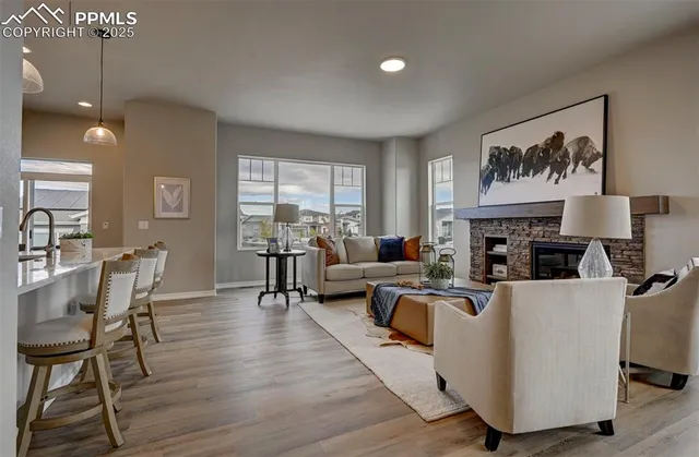 a living room with furniture a fireplace and a dining table with wooden floor
