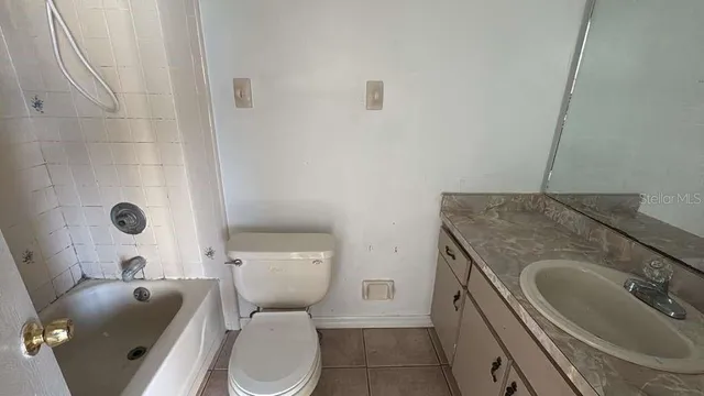 a bathroom with a granite countertop toilet sink and mirror