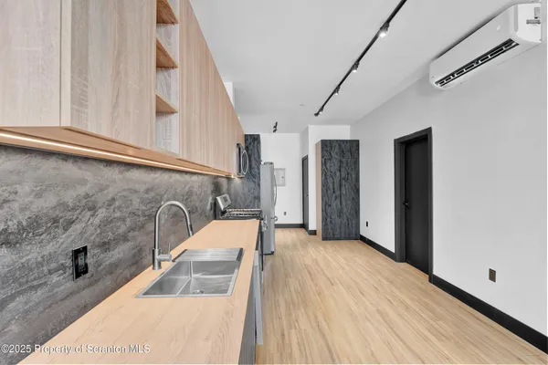 a kitchen with stainless steel appliances a stove top oven a sink dishwasher a refrigerator and a oven with wooden floor