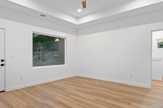 a view of an empty room with wooden floor and a window
