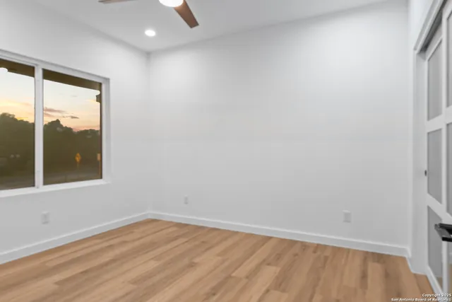an empty room with wooden floor and windows