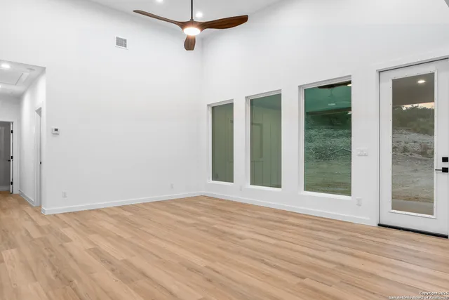 a view of an empty room with wooden floor and a window