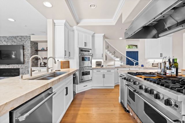 a kitchen with stainless steel appliances granite countertop a sink cabinets and a refrigerator