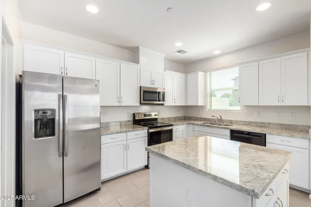 a kitchen with white cabinets appliances a sink and a window