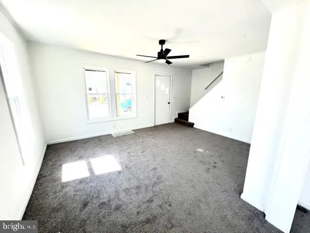 an empty room with windows and fan