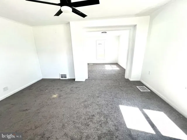 an empty room with a ceiling fan and carpet