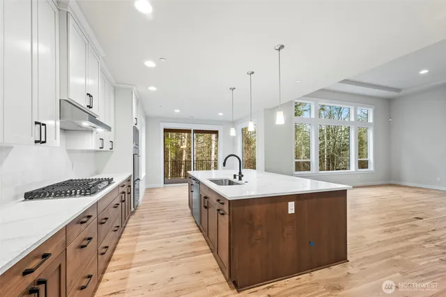 a large kitchen with kitchen island a sink stove and wooden floor