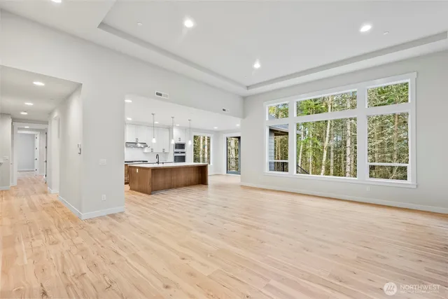 a view of kitchen with kitchen island a sink wooden floor and a large window