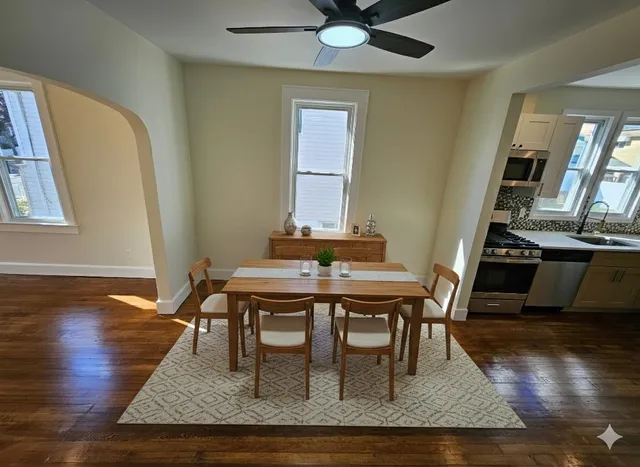 a dining room with wooden floor a chandelier a wooden table and chairs