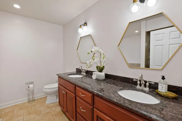 a bathroom with a granite countertop sink a toilet and a mirror