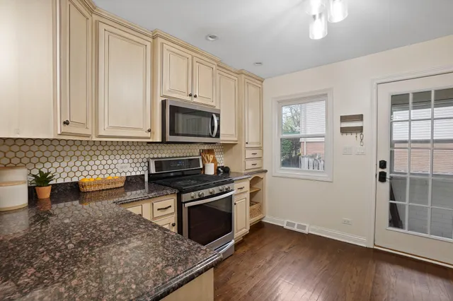a kitchen with stainless steel appliances granite countertop a stove a sink and a microwave