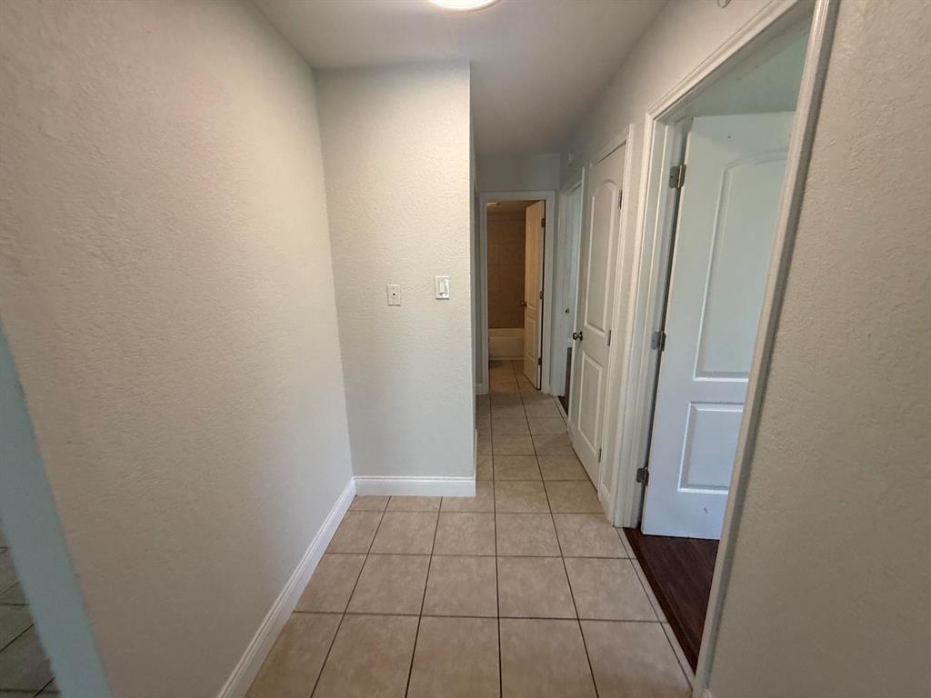312 West Rentz Street, Unit 93 Weatherford, TX 76086 - Photo 15 of 15 Hallway featuring neutral wall tones, square tile flooring, white baseboards, and multiple panel doors