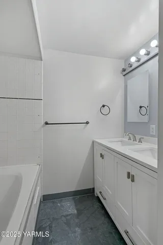 a bathroom with a tub sink and mirror