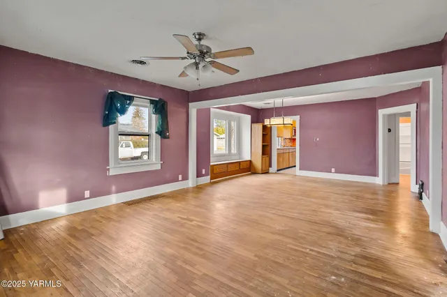 a view of an empty room with window and wooden floor
