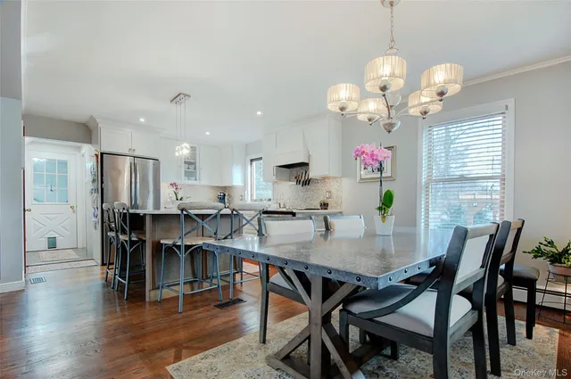 a kitchen with stainless steel appliances a table chairs refrigerator and wooden floor