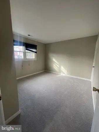 an empty room with windows and refrigerator