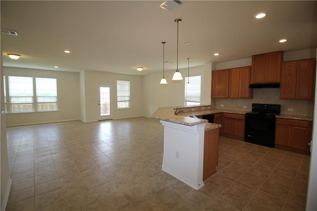 7200 Altidore Drive Austin, TX 78744 - Photo 3 of 23 a kitchen with a stove a sink a center island a counter top space and cabinets