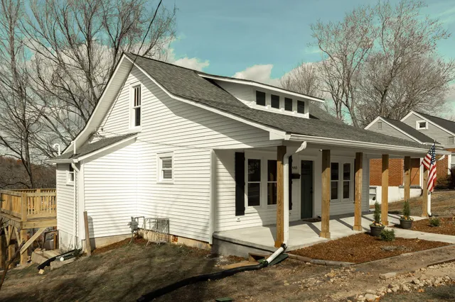 a view of a white house with large windows and wooden fence