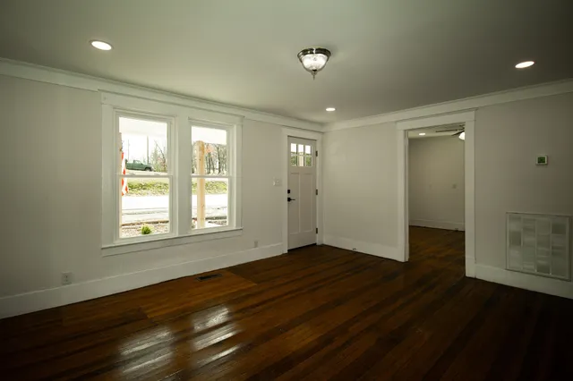 a view of an empty room with wooden floor and a window