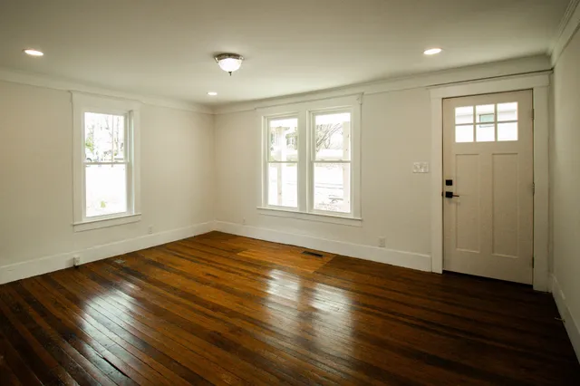 a view of an empty room with wooden floor and a window