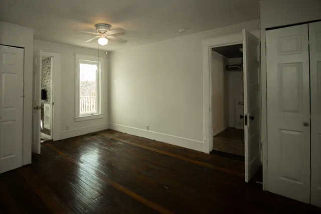 an empty room with wooden floor and windows