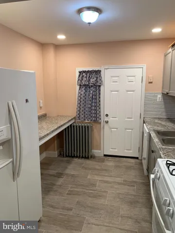 a view of kitchen with refrigerator and white cabinets