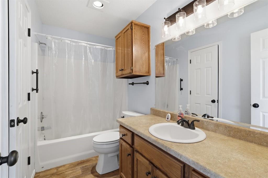 1974 County Road Powderly, TX 75473 - Photo 18 of 28 a bathroom with a granite countertop sink toilet a mirror a vanity and bathtub