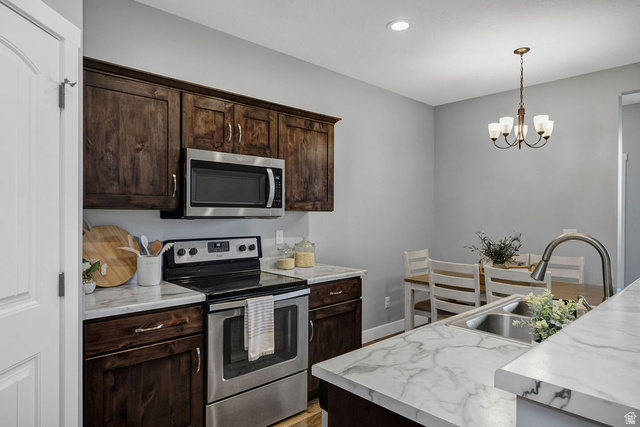 2483 South 1296th Street West Logan, UT 84321 - Photo 11 of 45 Kitchen featuring dark wood cabinetry, stainless steel appliances, and white marble-look countertops
