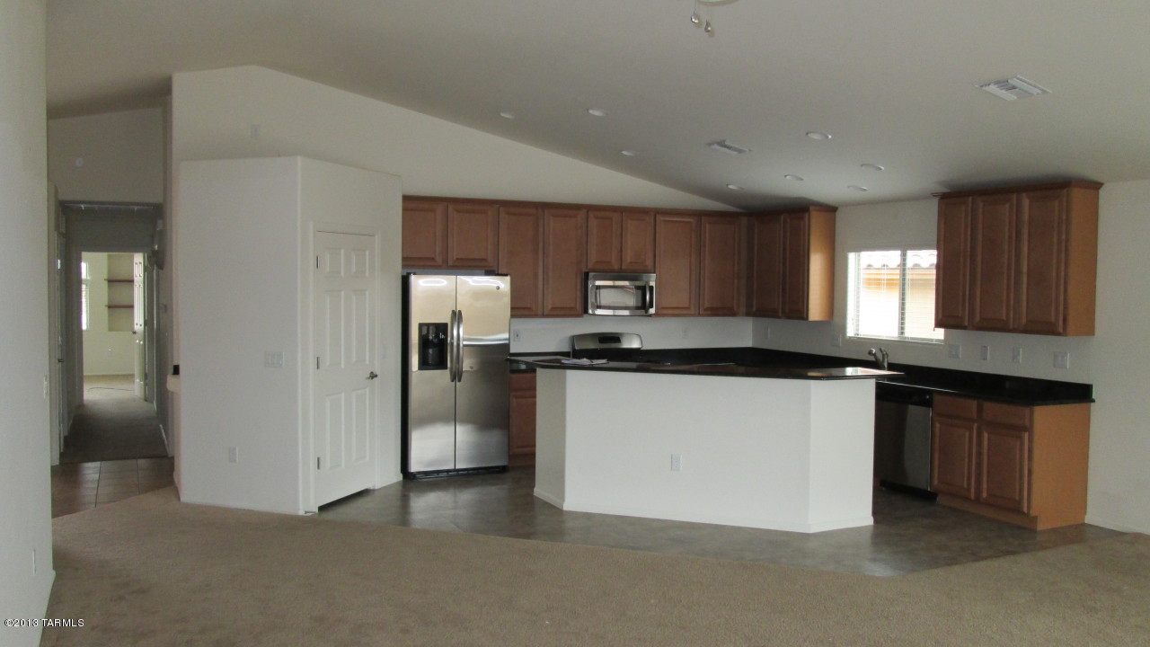 10855 East New Rock Ridge Drive Vail, AZ 85641 - Photo 9 of 34 a kitchen with stainless steel appliances granite countertop wooden cabinets a sink and a refrigerator