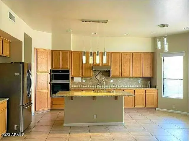 a large kitchen with stainless steel appliances kitchen island granite countertop a refrigerator and a sink