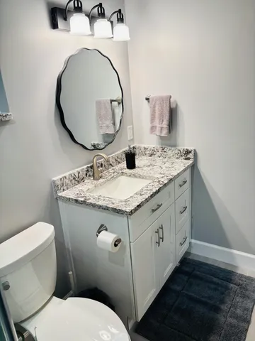 a bathroom with a granite countertop toilet sink and mirror
