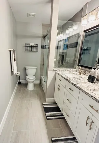 a spacious bathroom with a granite countertop sink toilet and shower
