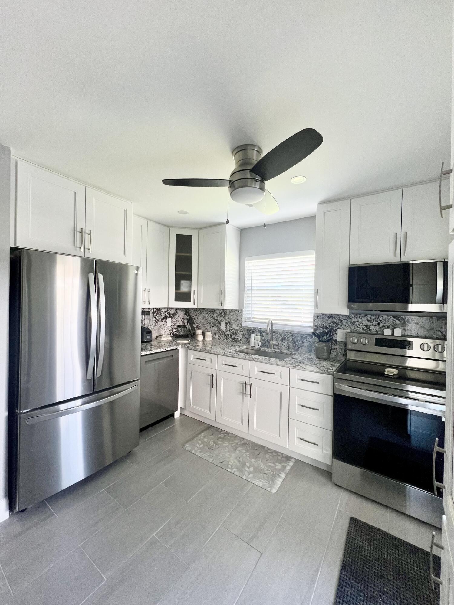 222 Southeast 3rd Street Boynton Beach, FL 33435 - Photo 3 of 40 a kitchen with granite countertop stainless steel appliances and wooden cabinets