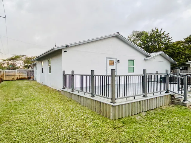 a view of a house with wooden deck and a backyard
