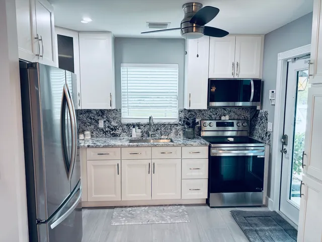 a kitchen with stainless steel appliances granite countertop a stove a refrigerator and a sink