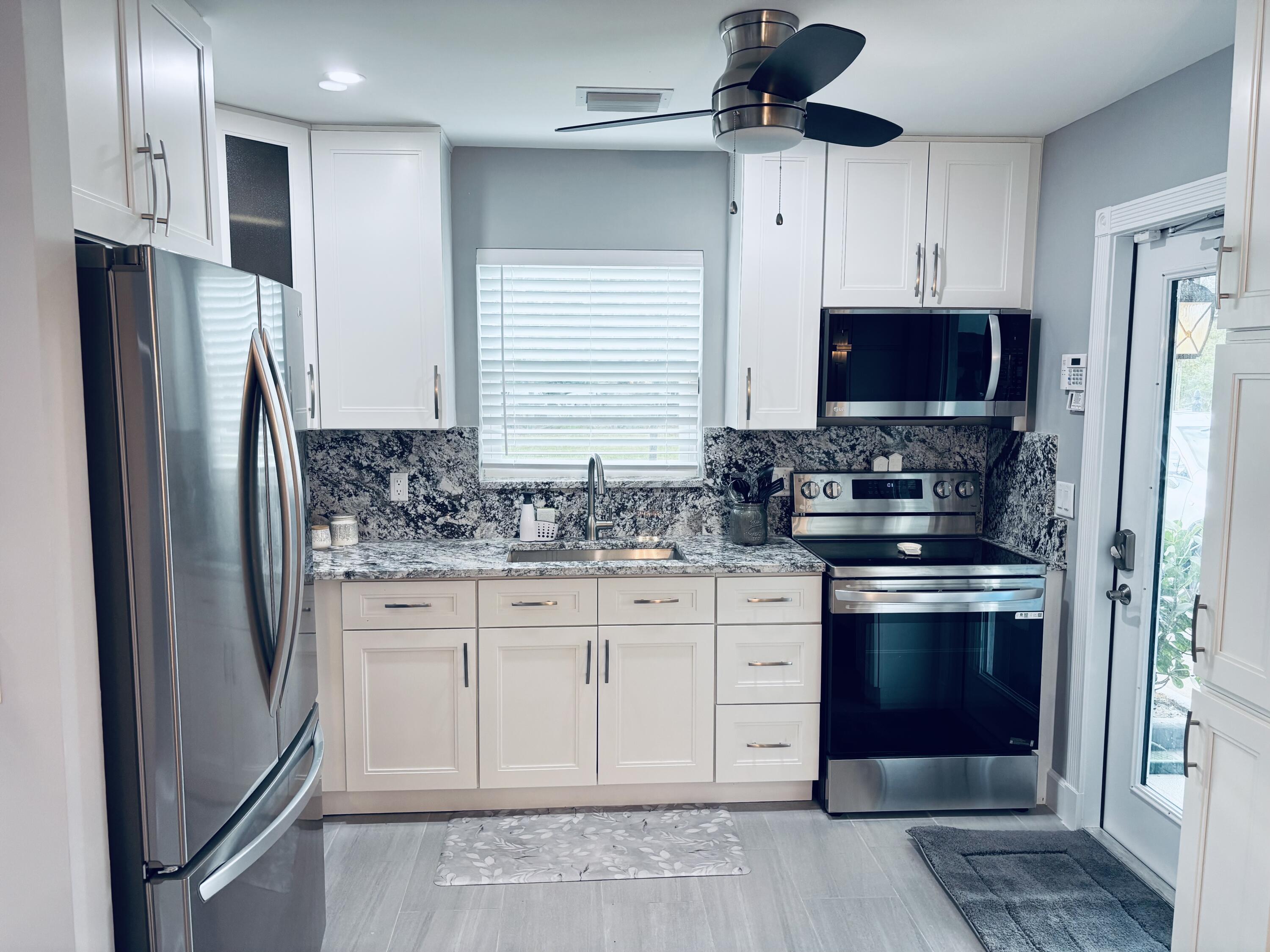 222 Southeast 3rd Street Boynton Beach, FL 33435 - Photo 4 of 40 a kitchen with stainless steel appliances granite countertop a stove a refrigerator and a sink