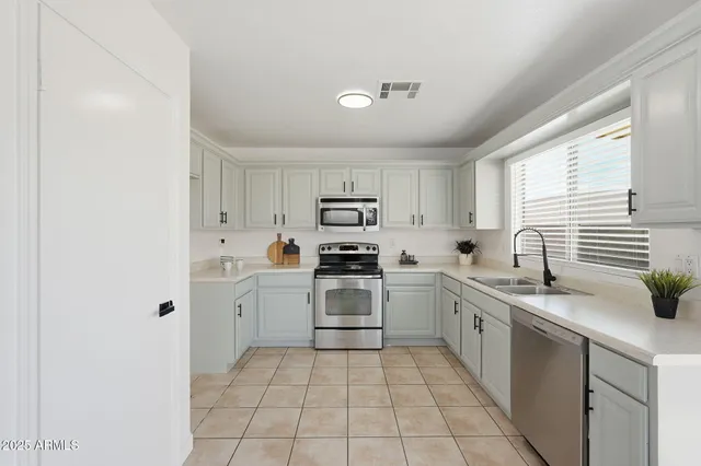 a kitchen with a sink white cabinets and white appliances