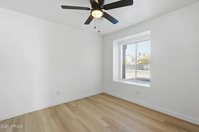 an empty room with chandelier fan and windows
