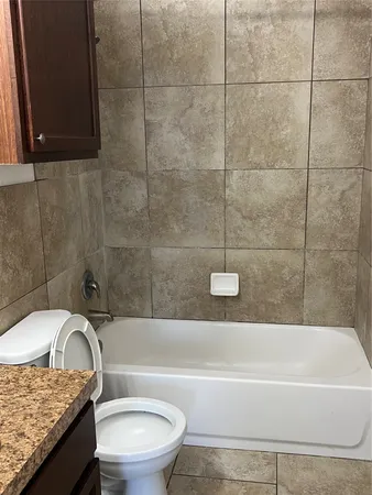 a bathroom with a granite countertop bathtub toilet and sink
