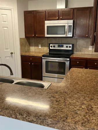 a kitchen with stainless steel appliances granite countertop a stove a sink and a microwave