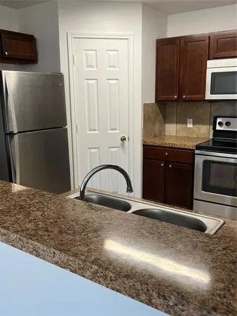 a kitchen with granite countertop a refrigerator stove and sink