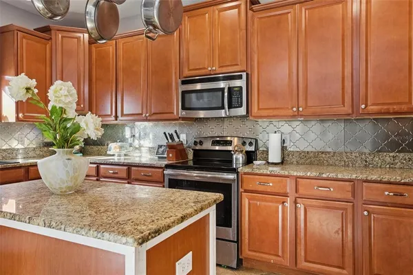 a kitchen with stainless steel appliances granite countertop a stove a sink and a microwave