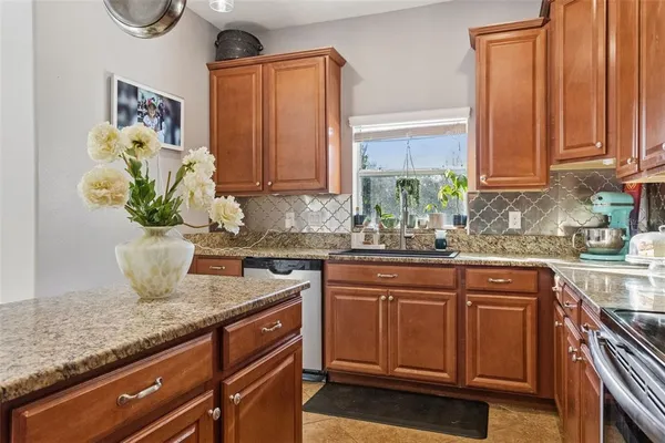 a kitchen with stainless steel appliances granite countertop a sink a stove and a wooden cabinets