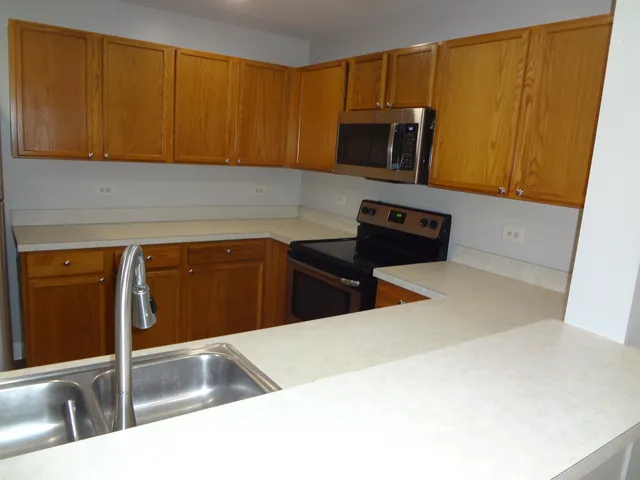 a kitchen with stainless steel appliances wooden cabinets a sink and a microwave