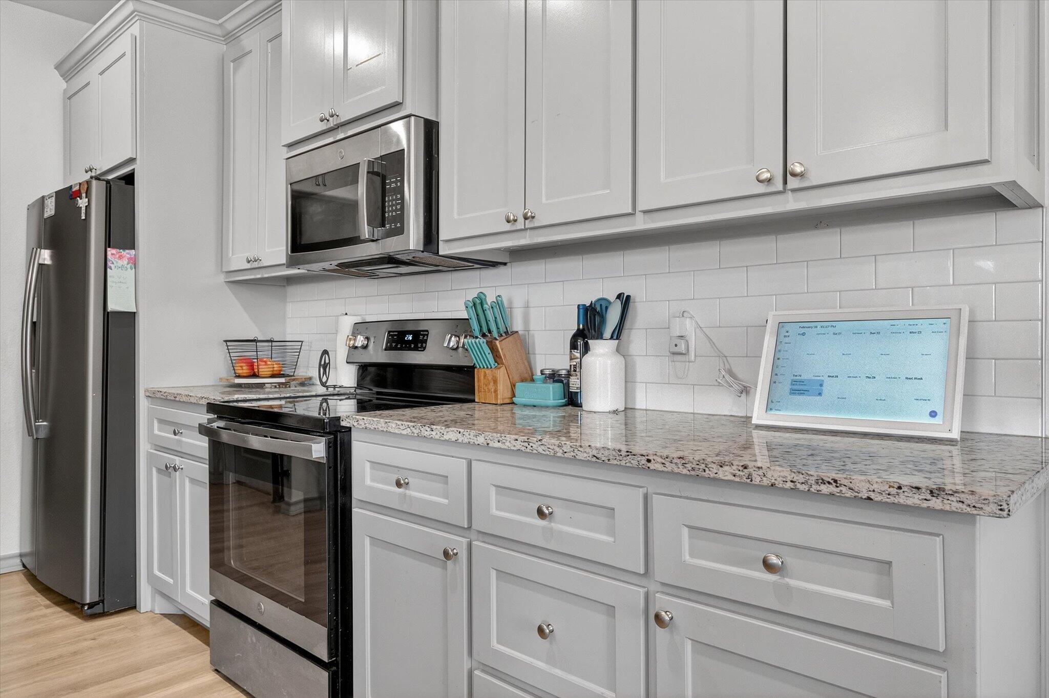 187 Allison Road Wilson, TX 79381 - Photo 12 of 35 a kitchen with granite countertop white cabinets stainless steel appliances and sink