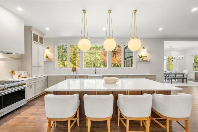 a large kitchen with kitchen island a sink dishwasher a stove a dining table and chairs with wooden floor