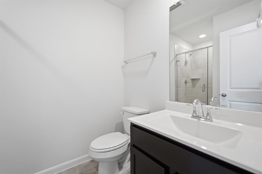 1908 Sangallo Lane Celina, TX 75009 - Photo 13 of 35 Bathroom featuring a dark wood-finish vanity with an integrated sink, polished chrome fixtures, a frameless mirror, and a glass-enclosed shower with tiled walls